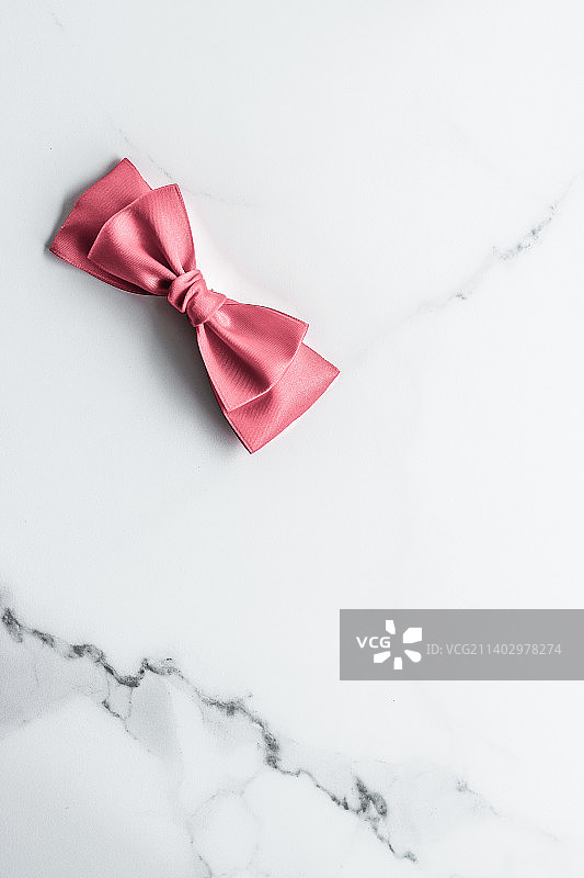 大理石背景上的珊瑚色丝带和蝴蝶结，女婴欢迎会图片素材
