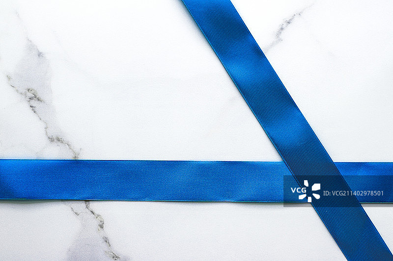奢华大理石背景上的蓝色丝绸带和蝴蝶结节日平面设计图片素材