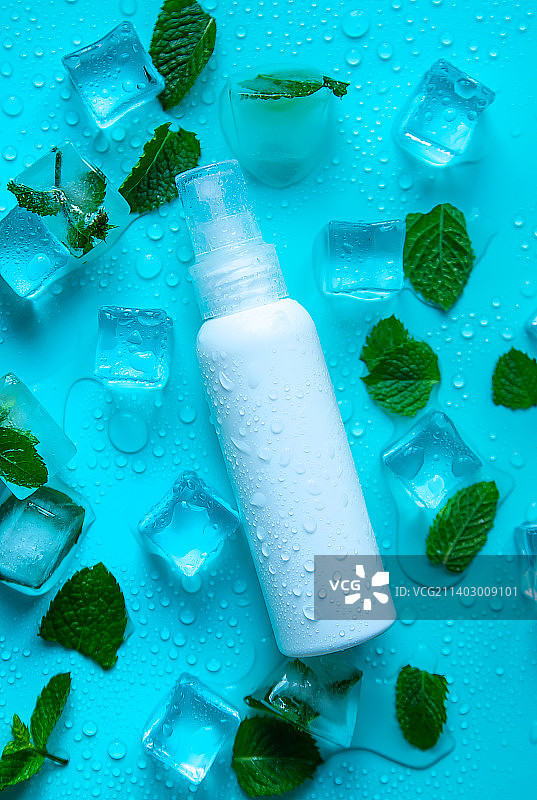 薄荷色背景上的化妆品瓶和冰块图片素材