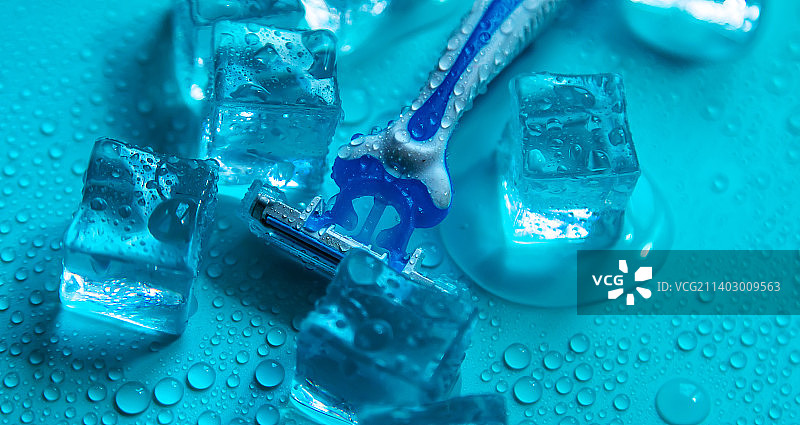 蓝色背景上的剃须刀和冰块特写图片素材