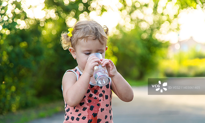 儿童喝玻璃杯中的水（选择性聚焦）图片素材