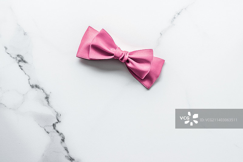 大理石背景上的粉色丝绸缎带和蝴蝶结，女婴欢迎会图片素材