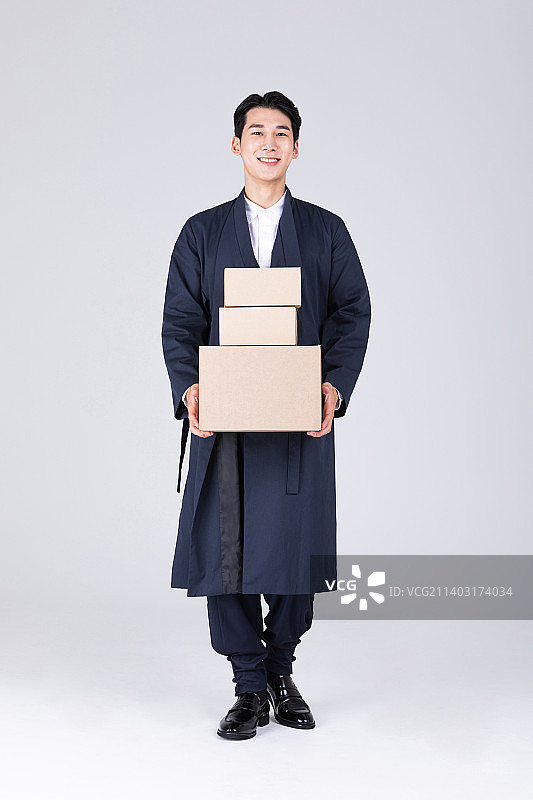 穿着现代韩服手提送货箱的韩国青年男人图片素材