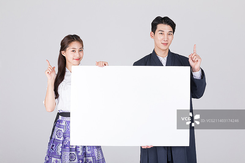 身穿现代韩服的20多岁韩国情侣，手持留白面板图片素材