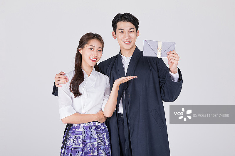 韩国情侣：身穿现代韩服的20多岁年轻男女，手拿韩国传统婚礼手包、红包图片素材