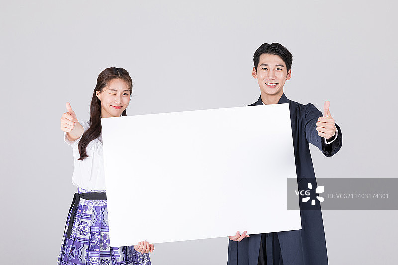 身穿现代韩服的20多岁韩国情侣，手持留白面板图片素材