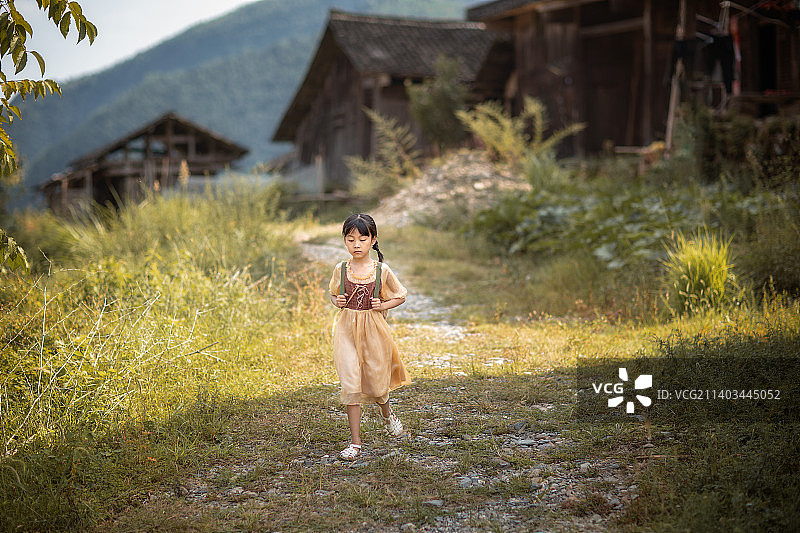 乡下老房子旁有一个背着背篓的小女孩图片素材