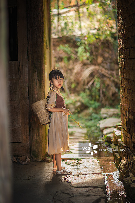 乡下老房子旁有一个背着背篓的小女孩图片素材