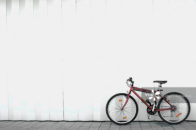 红色自行车，白色墙面背景图片素材