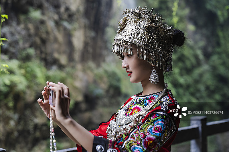 恩施大峡谷里区里用手机拍照的苗族姑娘图片素材