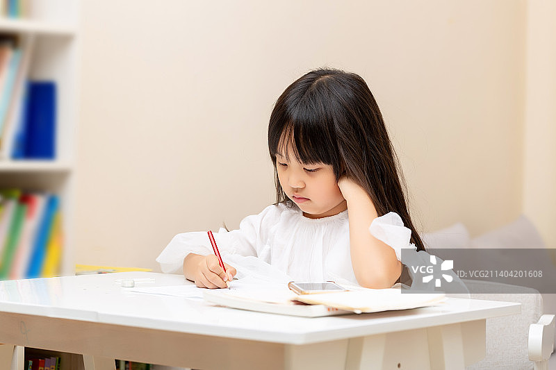 坐在桌前写作业的中国小女孩图片素材