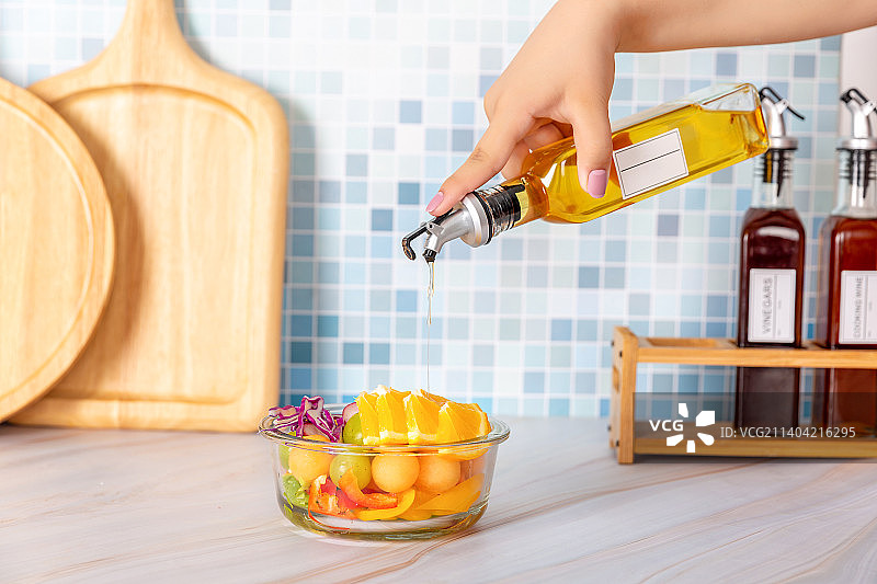手拿油瓶在玻璃碗里的轻食果蔬图片素材