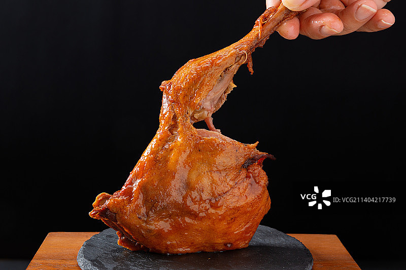 黑色背景前的熟食鸭腿图片素材