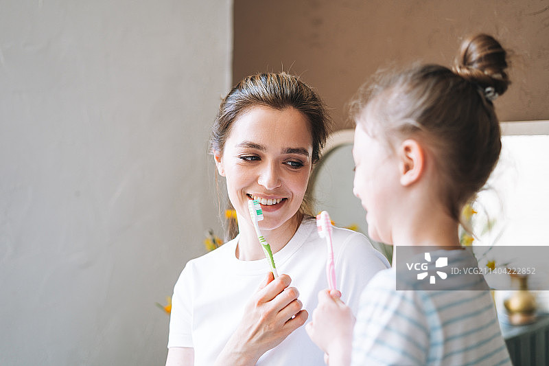 年轻的母亲和穿着睡衣的小女儿早上在家刷牙图片素材