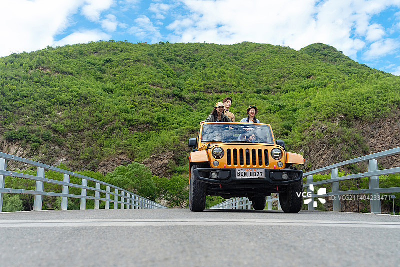 从汽车天窗探出身子兜风的年轻男女图片素材