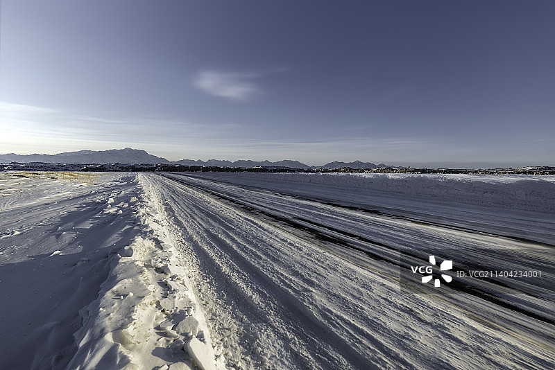 冬季雪山雪地轮胎印道路日落逆光图片素材