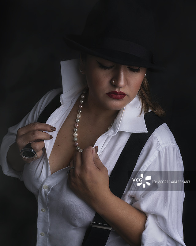 戴帽子的女人站在黑色背景前，英国图片素材