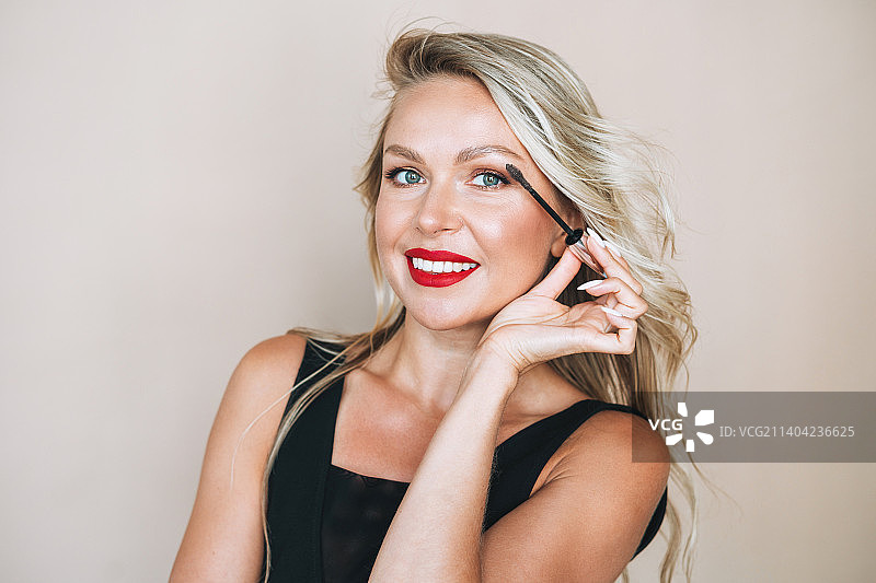 化着鲜艳妆容、身穿晚礼服的女子肖像，背景为米色图片素材