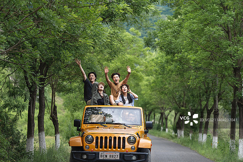 从汽车天窗探出身子兜风的年轻男女图片素材