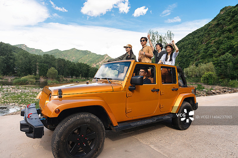 从汽车天窗探出身子兜风的年轻男女图片素材