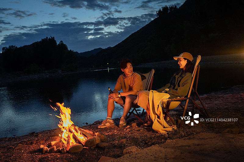 年轻情侣夜晚在野外篝火露营图片素材