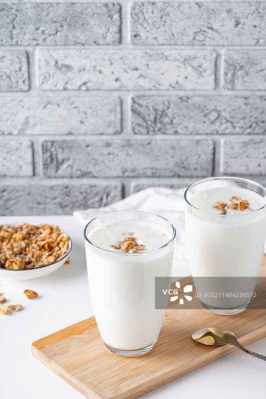 浅色背景玻璃杯中的开菲尔酪乳或酸奶格兰诺拉麦片图片素材