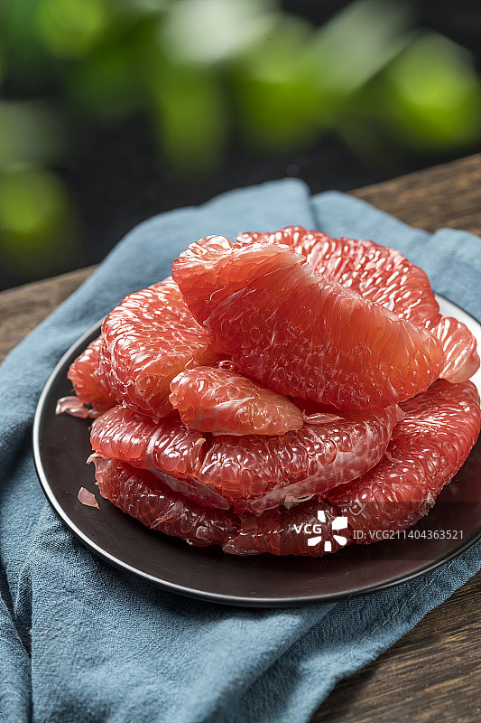 一盘红心柚子摆放在木桌面上特写图片素材