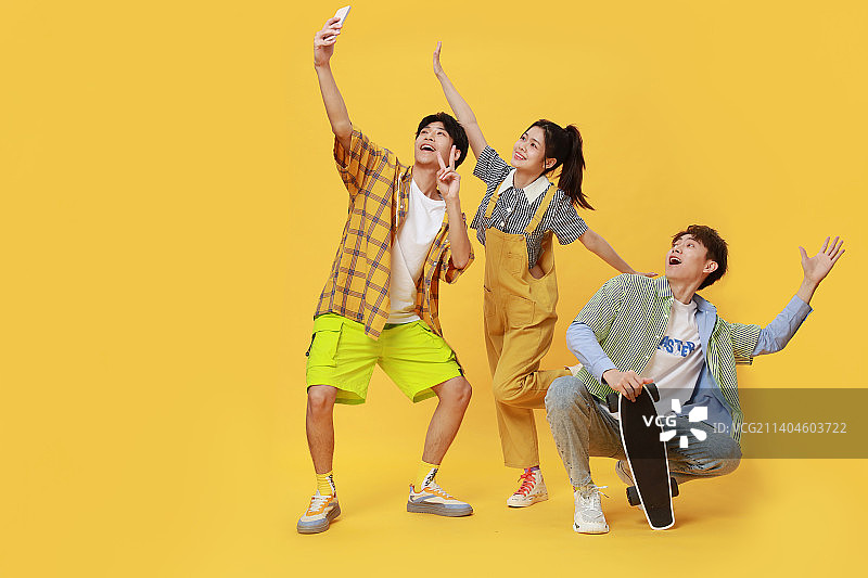 玩着滑板用手机拍视频的年轻男女图片素材