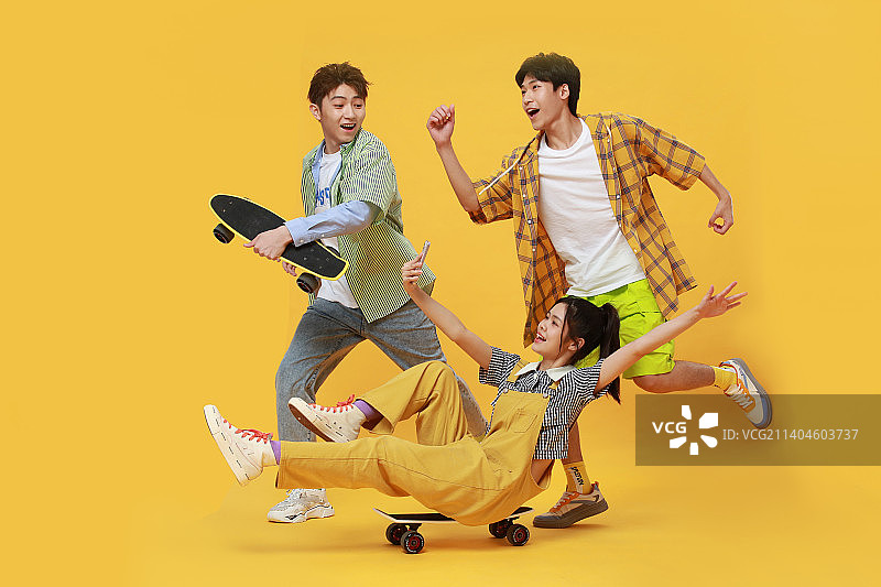 推着坐在滑板上的年轻男女图片素材