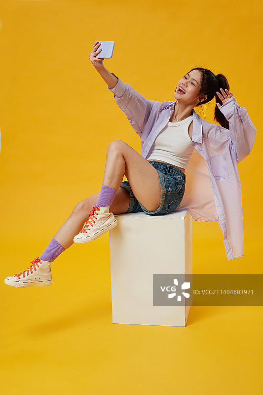 坐在木箱上的年轻女孩使用手机图片素材