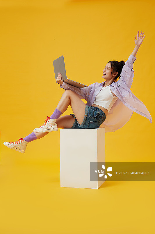 手拿笔记本坐在木箱子上的年轻女孩图片素材