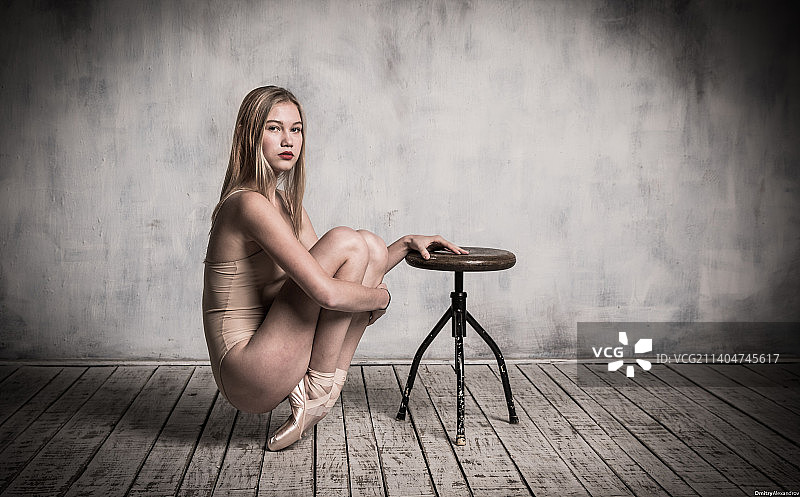 蹲在硬木地板上靠墙的女子肖像图片素材