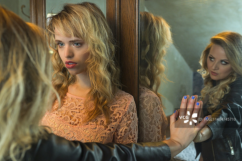 在浴室里，镜子中映出倒影的两位女性，比利时鲁汶图片素材