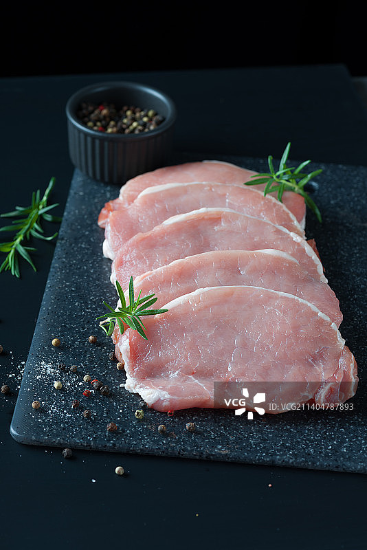 生猪肉片，黑色背景，顶视图。图片素材