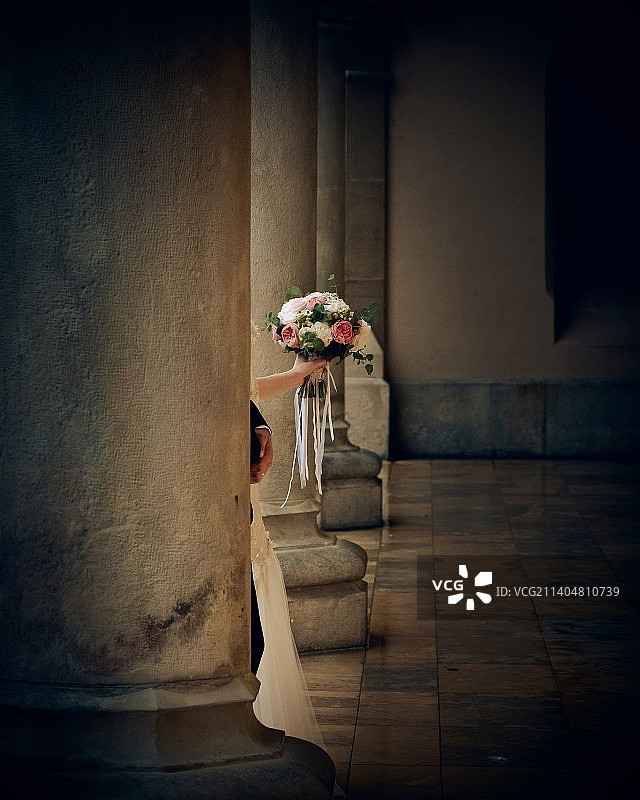 手捧鲜花站在柱子后面的新婚夫妇肖像图片素材