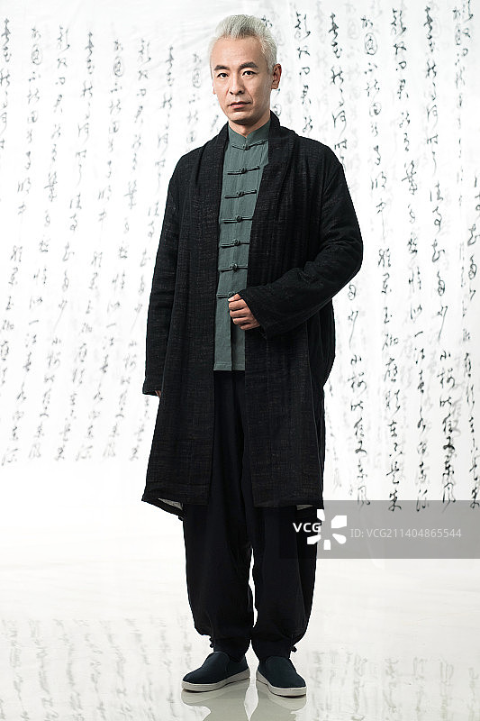 身穿中式服装的男人站在书法前图片素材