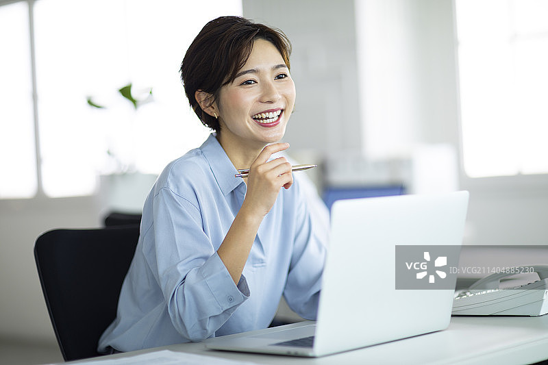 在办公桌前微笑工作的女人图片素材