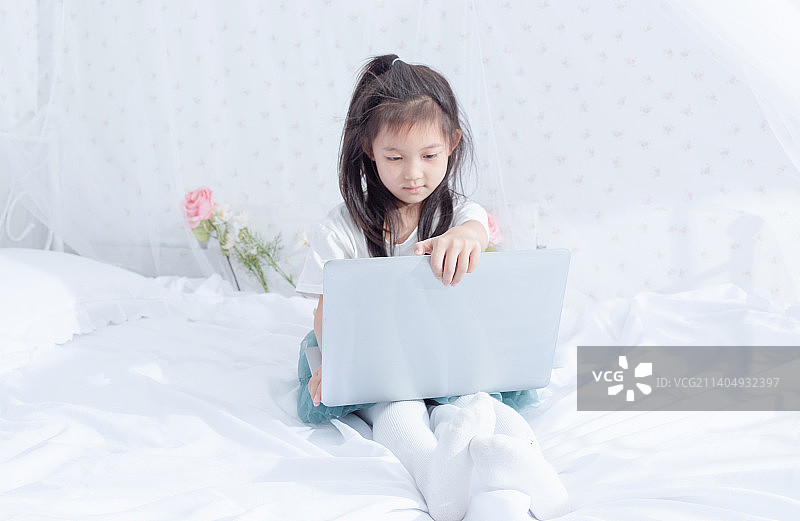 在床上使用笔记本电脑的小女孩图片素材