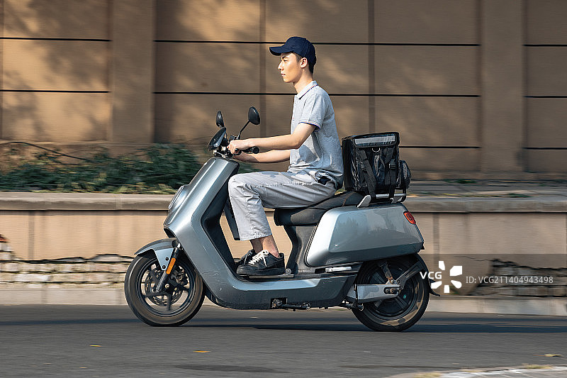 骑着电动车送货的男外卖员图片素材