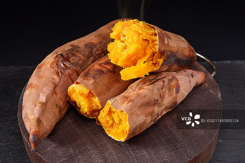 木板上掰开冒着热气的烤红薯图片素材