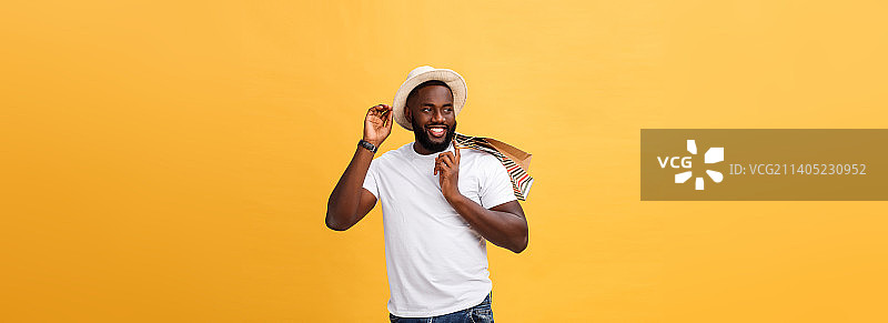 快乐的非洲裔美国男人拿着购物袋，背景黄色图片素材