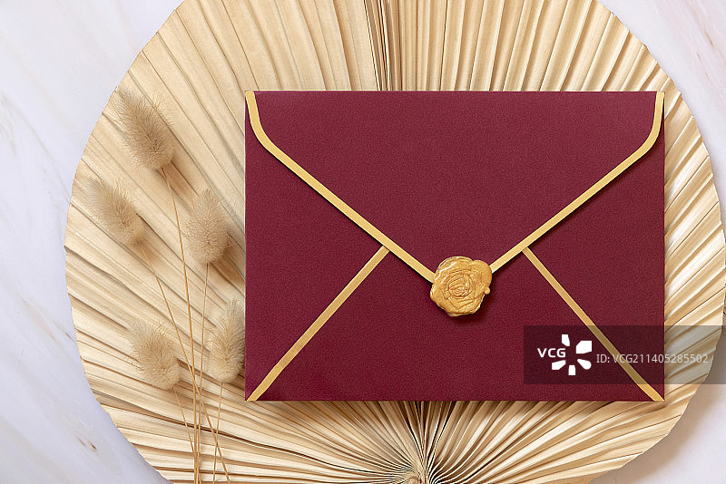 干燥的米色棕榈叶附近的红色信封，兔尾草顶部视图，波西米亚婚礼模型图片素材