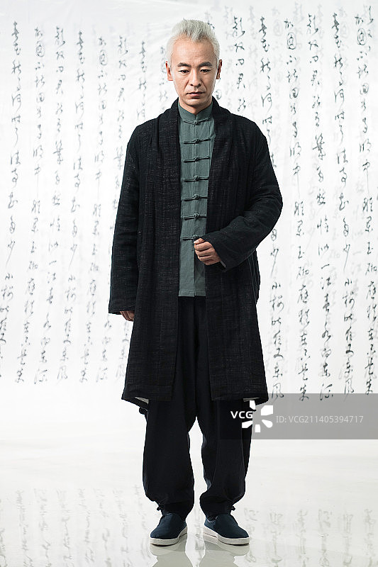 身穿中式服装的男人站在书法前图片素材