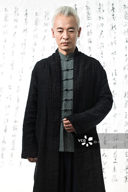 身穿中式服装的男人站在书法前图片素材