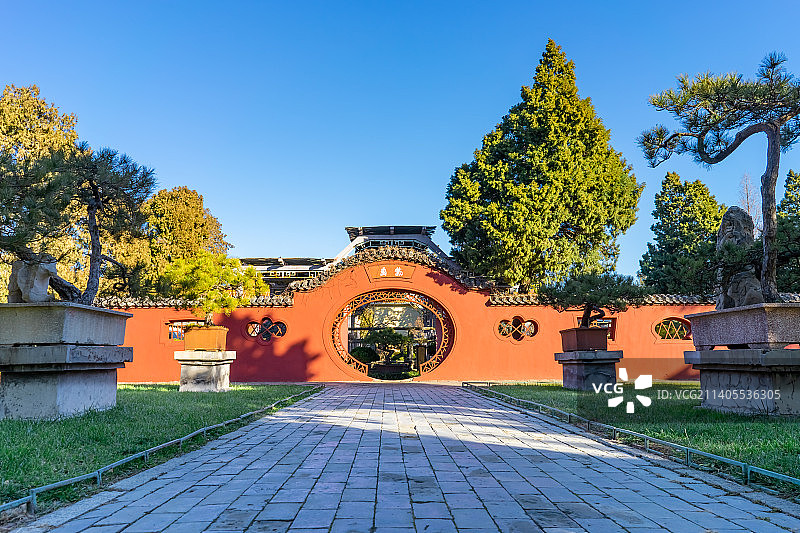 中国山东泰安著名景点泰山旅行旅游目的地，泰山第一行宫岱庙，素景中式庭院里的月亮门和花坛，户外白昼无人图片素材