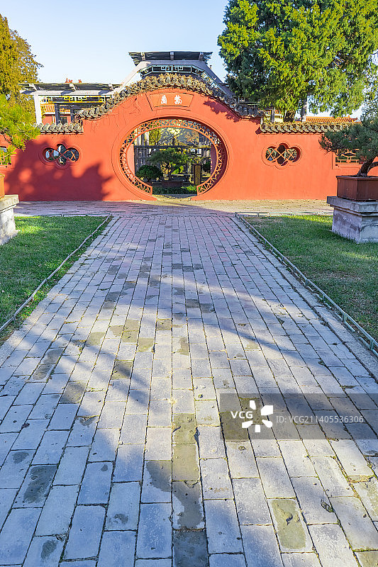 中国山东泰安著名景点泰山旅行旅游目的地，泰山第一行宫岱庙，素景中式庭院里的月亮门和花坛，户外白昼无人图片素材