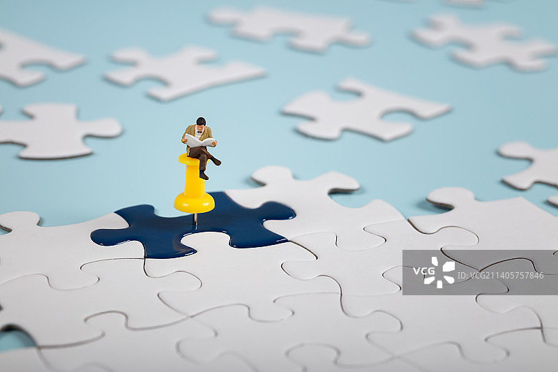 微缩创意在拼图上看报纸的人图片素材