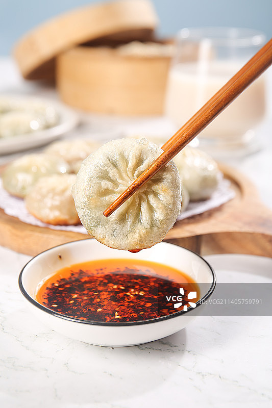 筷子夹着蘸酱的小包子图片素材