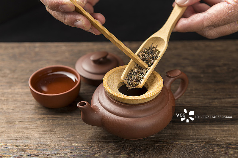 使用竹制茶则茶铲茶匙向紫砂壶中倒茶叶特写图片素材