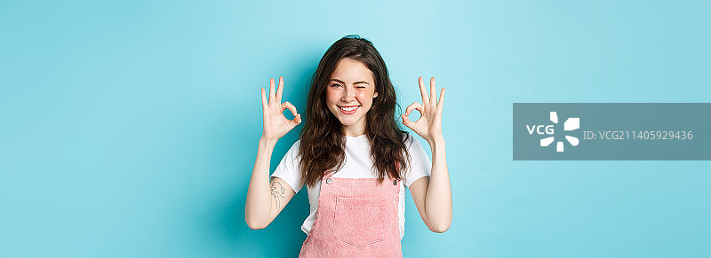 自信而积极的年轻女子眨眼微笑，表示没问题图片素材